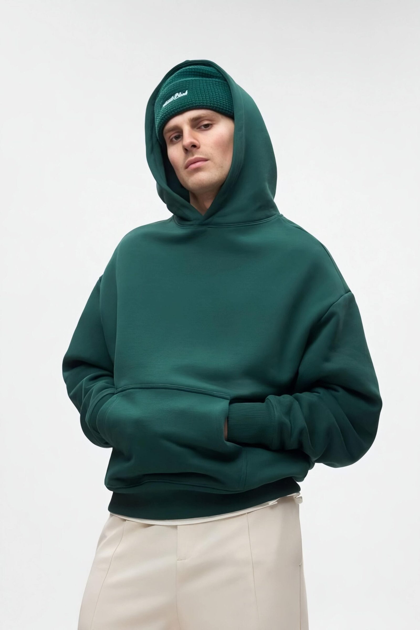 A male model wearing a dark green zerodas oversized hoodie with a front pocket and ribbed cuffs.