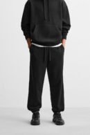 Model wearing Zerodas Classic Black Track Pant styled with hoodie, featuring relaxed fit and elastic cuffs
