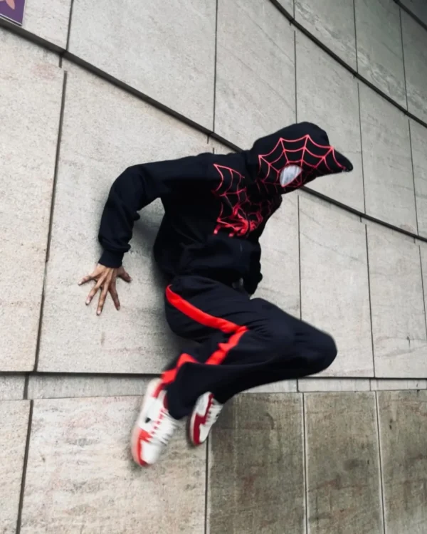Model wearing black Spiderman zip-up hoodie in urban setting